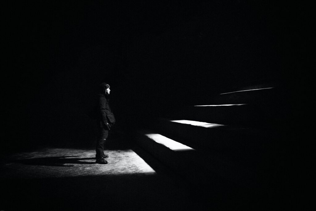 pessoa em um ambiente escuro, posicionada de frente uma escada iluminada por uma luz branca para simbolizar a tarifa branca de energia