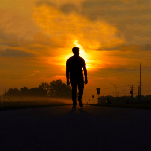 silhueta de um homem andando contra o sol