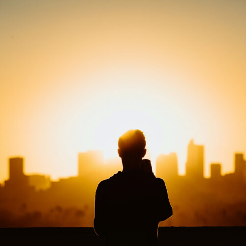 pessoa de pé olhando para prédios no pôr do sol