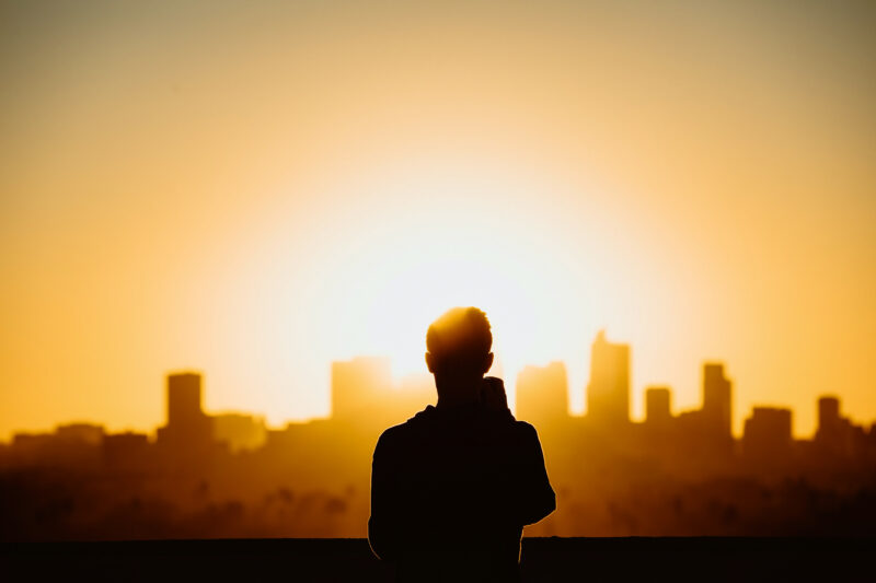 pessoa de pé olhando para prédios no pôr do sol